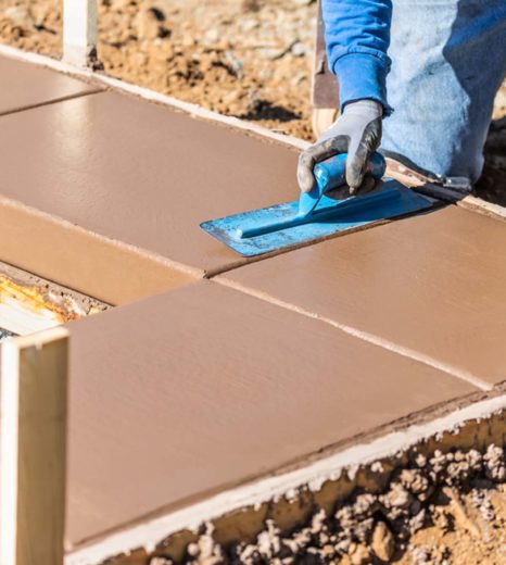 Construction Worker Using Trowel On Wet Cement Forming Coping Around New Pool - Turnkey Pool Designers