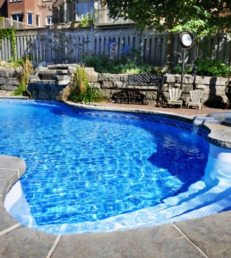 Residential inground swimming pool in backyard with waterfall and hot tub - Turnkey Pool Designers