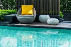 Relaxing chairs with pillows beside swimming pool - Turnkey Pool Designers