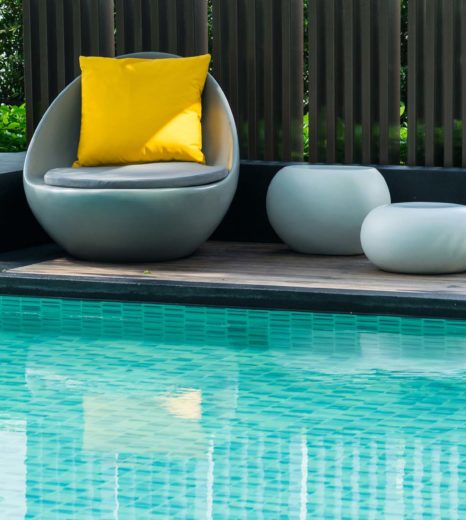 Relaxing chairs with pillows beside swimming pool - Turnkey Pool Designers