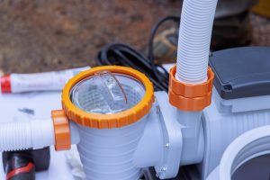 Worker assembles pool pump in an outdoor environment, paying attention to fitting details components.