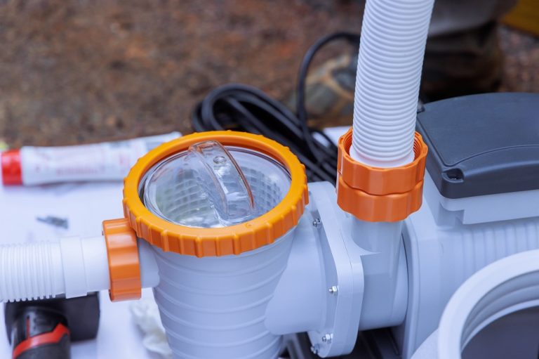 Worker assembles pool pump in an outdoor environment, paying attention to fitting details components.