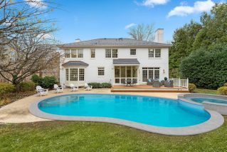 Backyard swimming pool and attached spa behind a white brick home in Baton Rouge