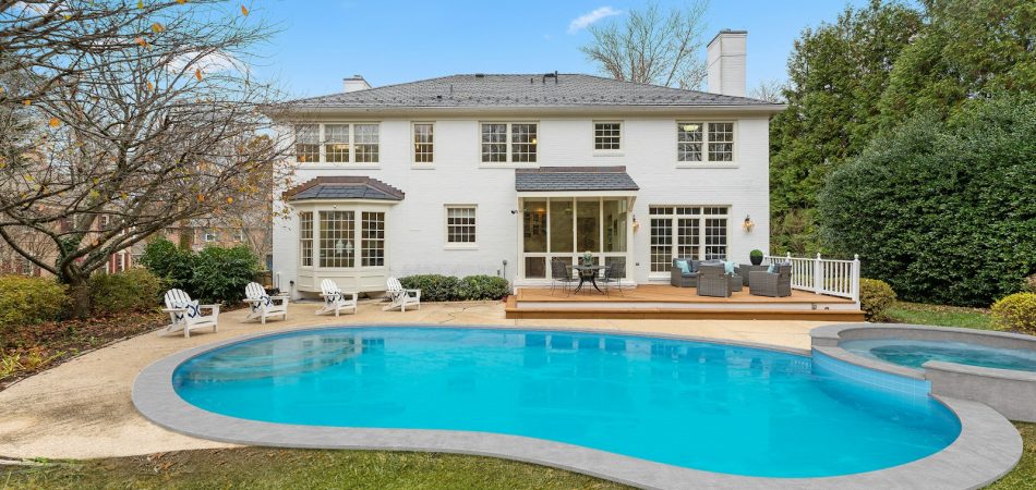 Backyard swimming pool and attached spa behind a white brick home in Baton Rouge