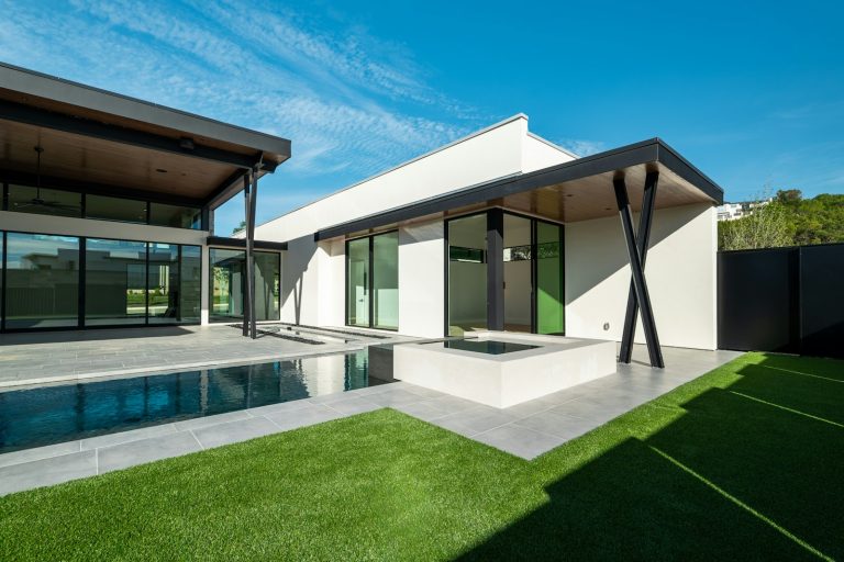 Modern Baton Rouge home with a rectangular pool and raised spa beside a tiled patio