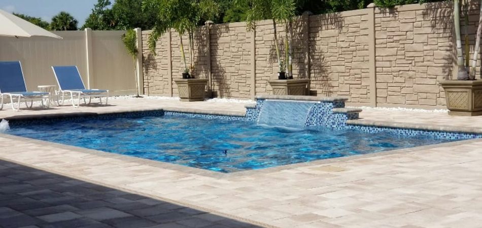 Gunite pool with a tiled sheer descent water feature and travertine deck