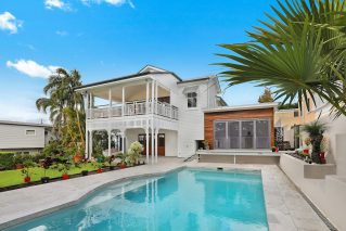 Raised white home in New Orleans with a custom inground pool and travertine deck
