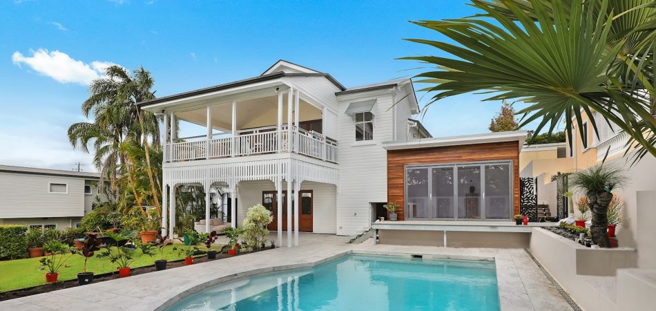 Raised white home in New Orleans with a custom inground pool and travertine deck