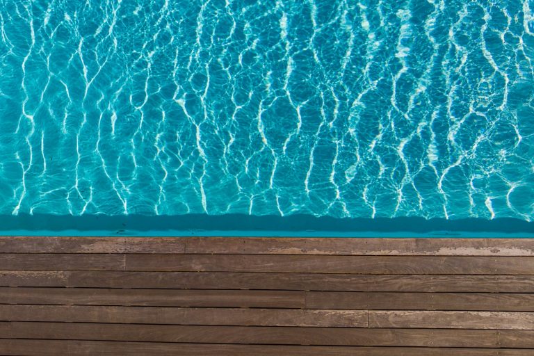 Clear pool water beside a timber pool deck, showing how decking affects total pool cost