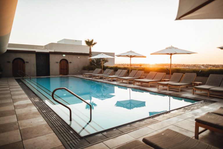 Pool surrounded by loungers and shade umbrellas at sunset, an example of outdoor living budget items