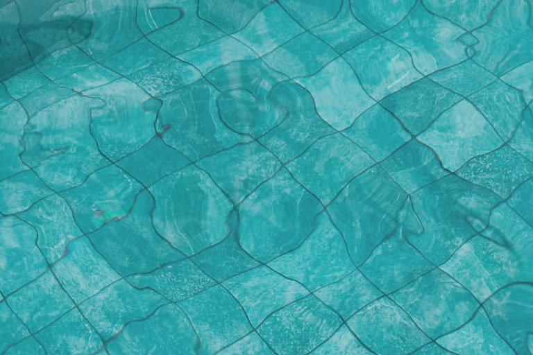 Close view of tiled pool floor under clear water, showing how interior surfaces wear over time