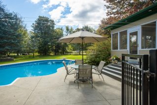 Backyard pool with patio seating and a screened porch on a suburban lot