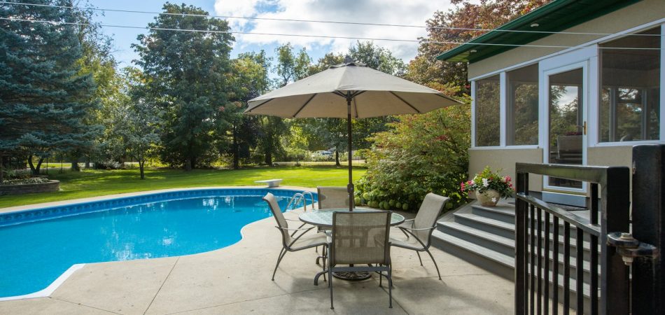 Backyard pool with patio seating and a screened porch on a suburban lot