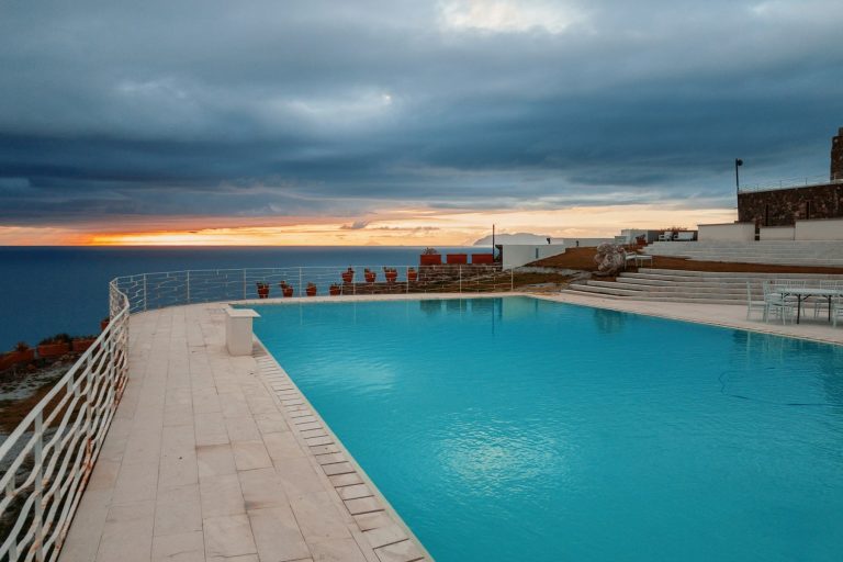 Pool terrace beside open water under gathering storm clouds