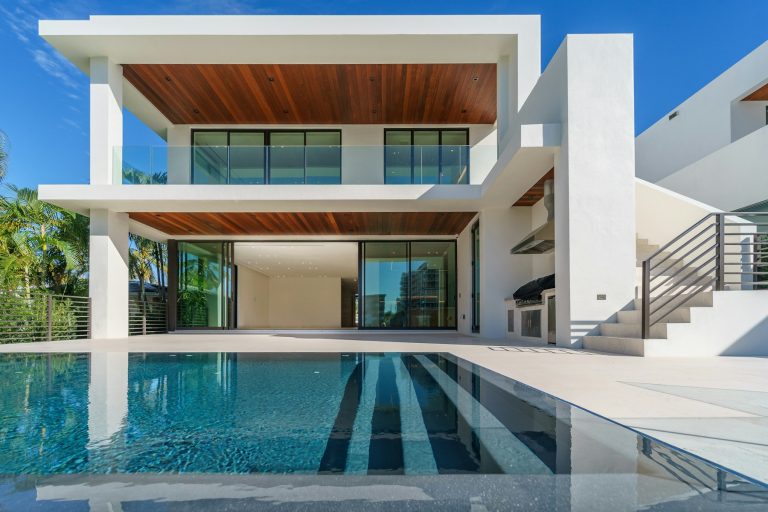Modern white home with a wide terrace reflected in a backyard pool