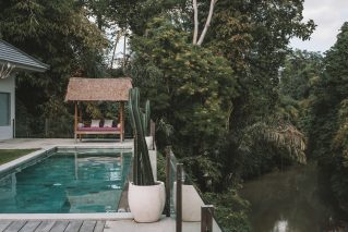 Backyard swimming pool beside a tree-lined waterway