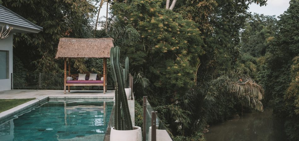 Backyard swimming pool beside a tree-lined waterway