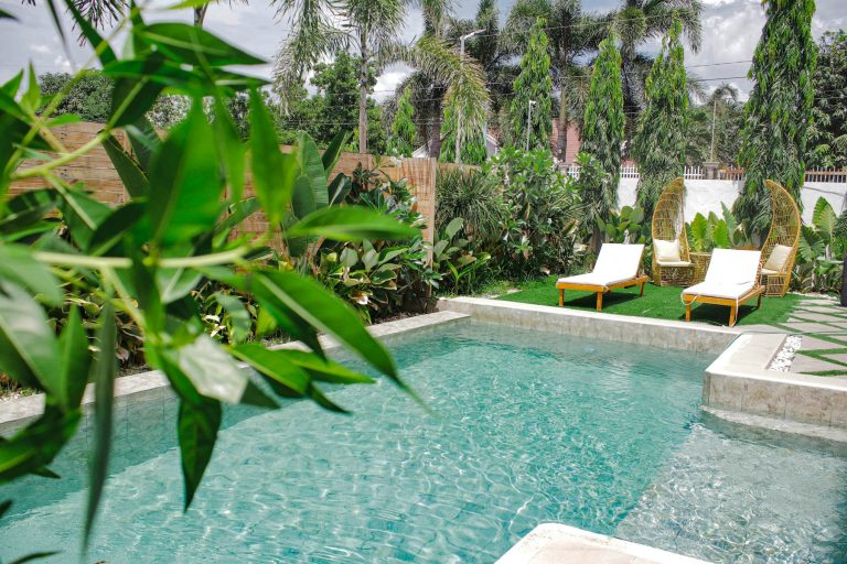 Swimming pool with chairs and dense planting around the deck
