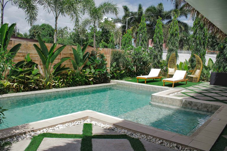 Backyard pool enclosed by a timber privacy fence and tropical planting