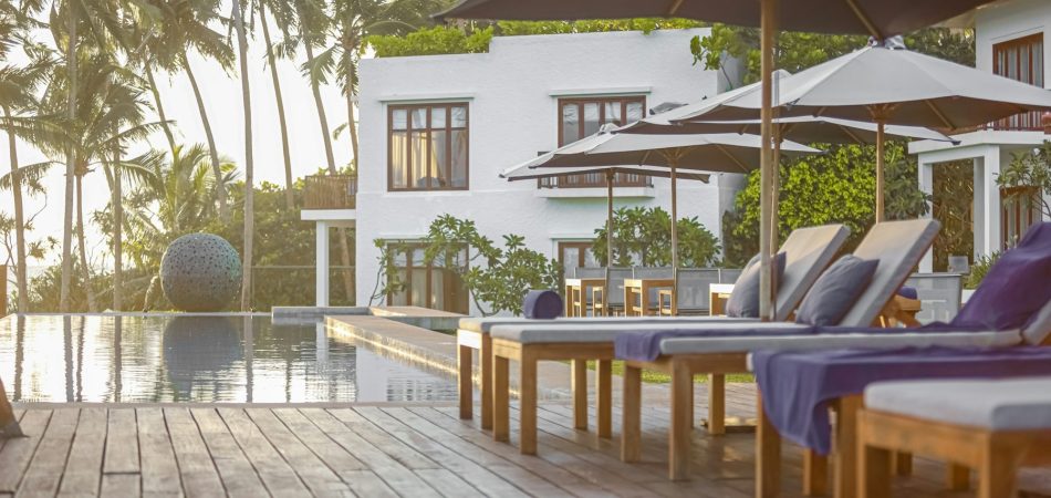 Timber pool deck with chairs and umbrellas beside a swimming pool