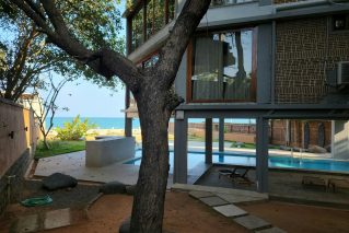Raised home on columns with a swimming pool and a mature tree in the yard