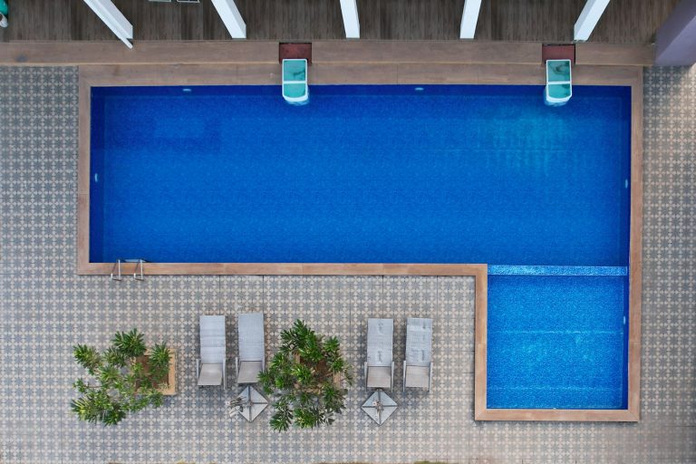 Overhead view of a rectangular pool with a shallow ledge, lounge chairs and potted plants
