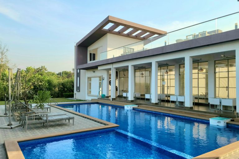 Long backyard pool running beside a covered veranda and sun deck