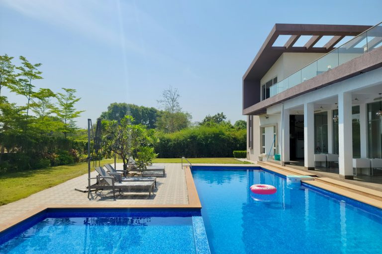 Large swimming pool with lounge chairs set back on a wide deck