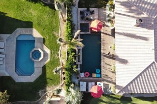 Aerial view of neighboring backyards with swimming pools and paved decks