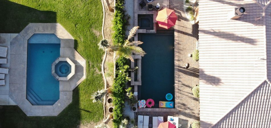 Aerial view of neighboring backyards with swimming pools and paved decks