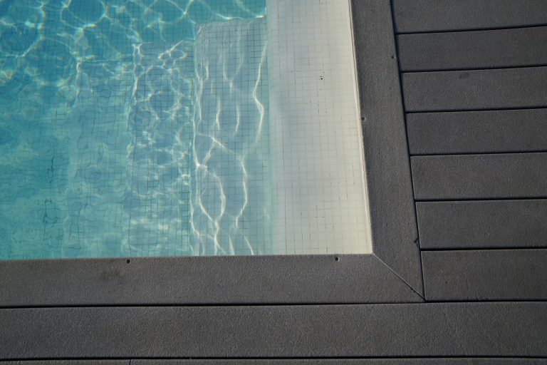 Rippling blue pool water meeting the edge of a pool deck