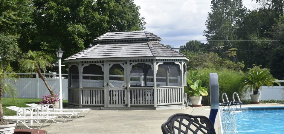 Fenced backyard pool area with a wooden gazebo and lounge chairs
